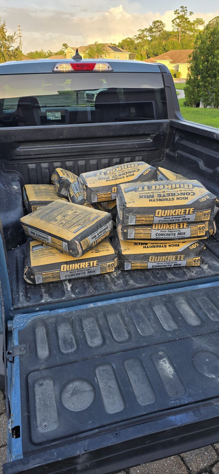 Pickup truck bed loaded with bags of Quikrete high strength concrete mix at golden hour