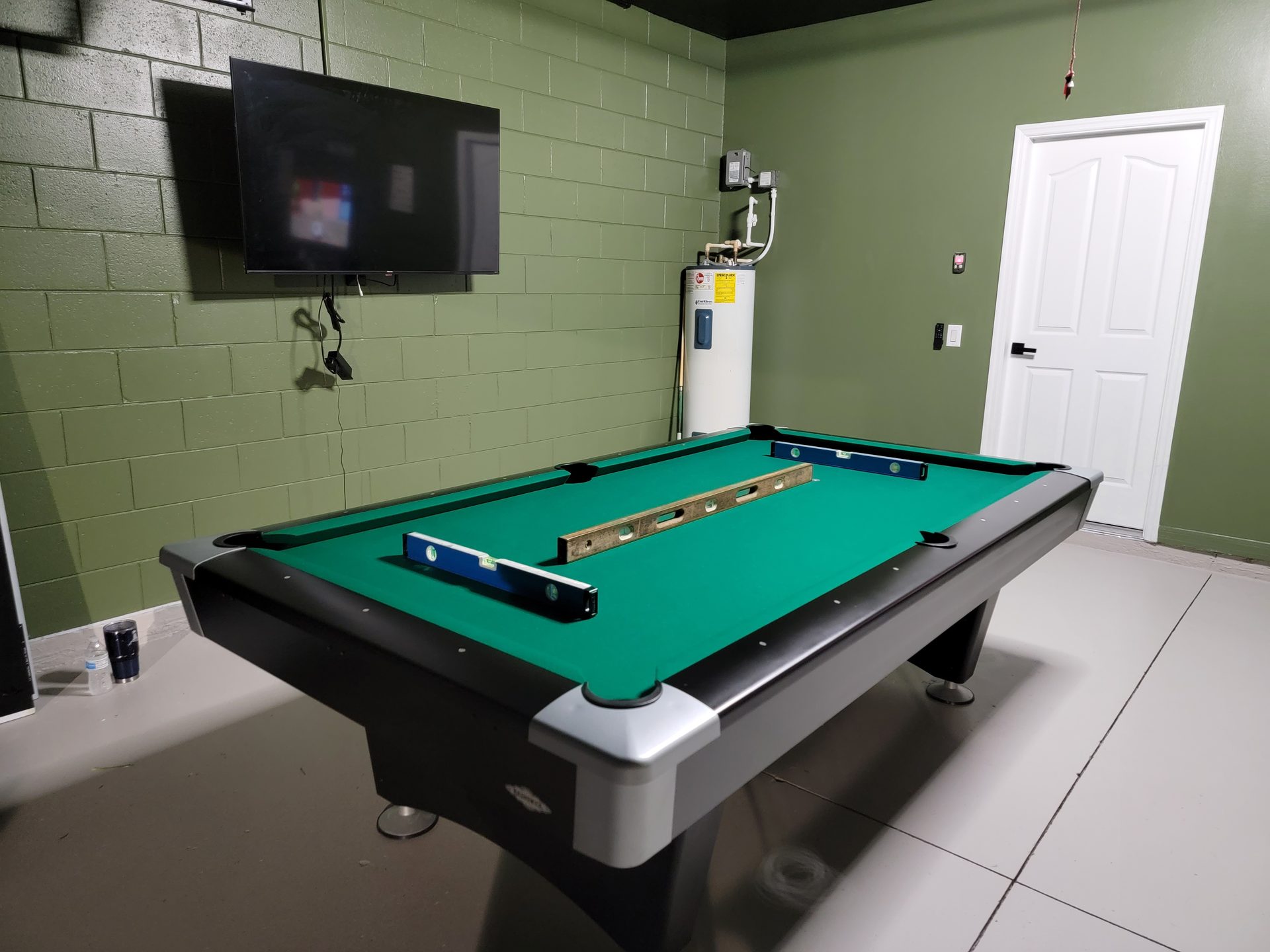 Finished pool table with green felt and machinist levels confirming dead-level slate installation