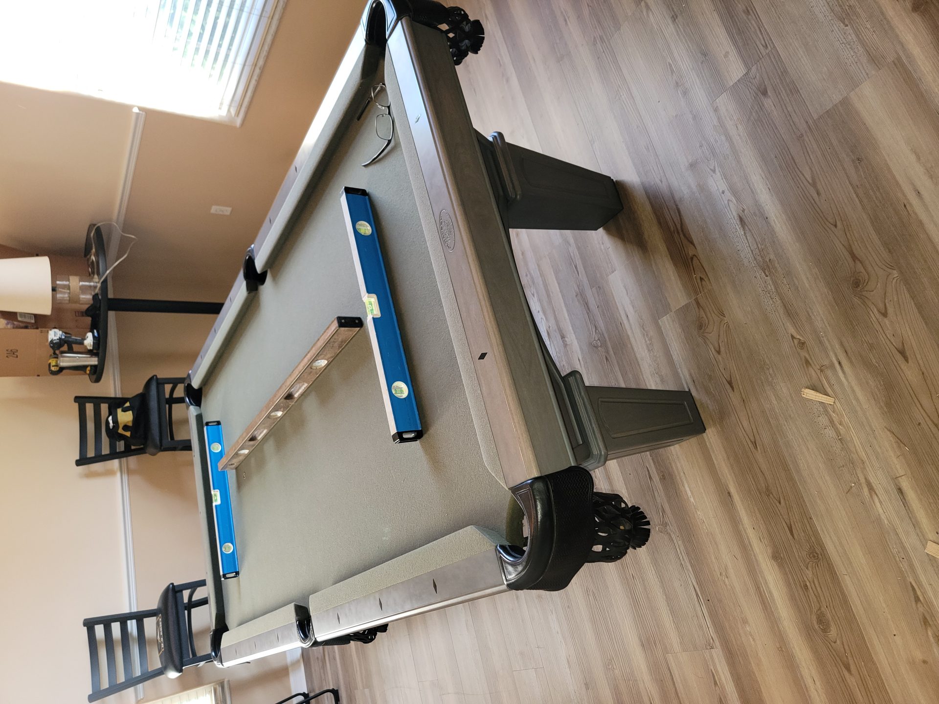 Grey felt pool table with blue machinist levels during the leveling process